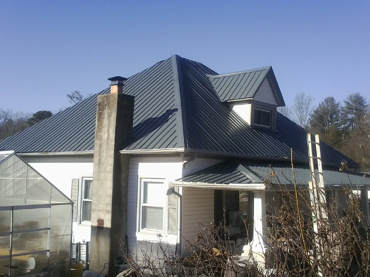 Dark blue standing seam metal roof on a white farmhouse with dormer — Slate & Tile Roof Repair by Roofing Brothers in Harrisonburg