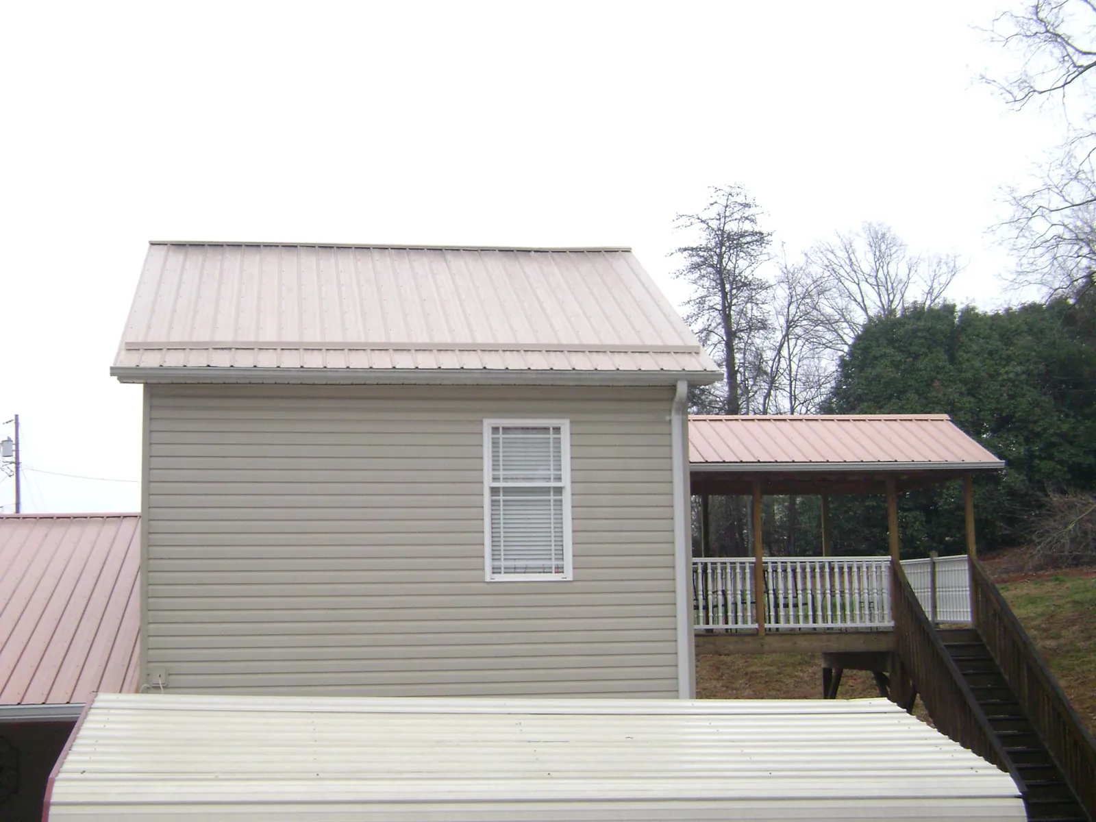 Tan metal roofs on a two story addition and attached porch, from a Roof Replacement job in Harrisonburg