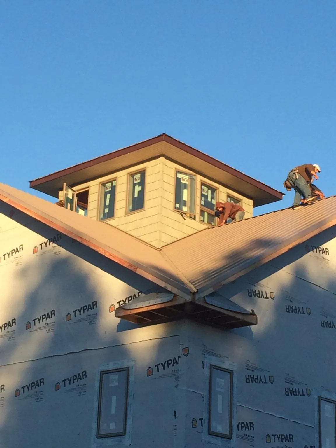 Roofers working around a rooftop cupola on a new metal roof at sunset — Roof Waterproofing in Harrisonburg by Roofing Brothers